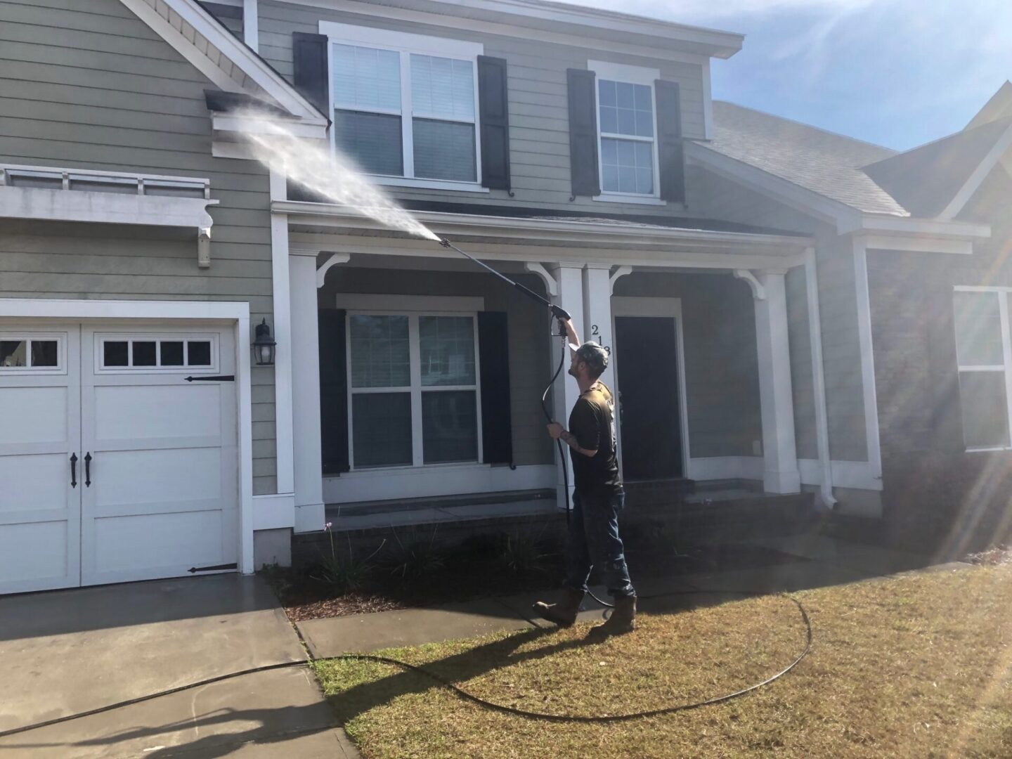 A man is spraying water from the roof of his house.