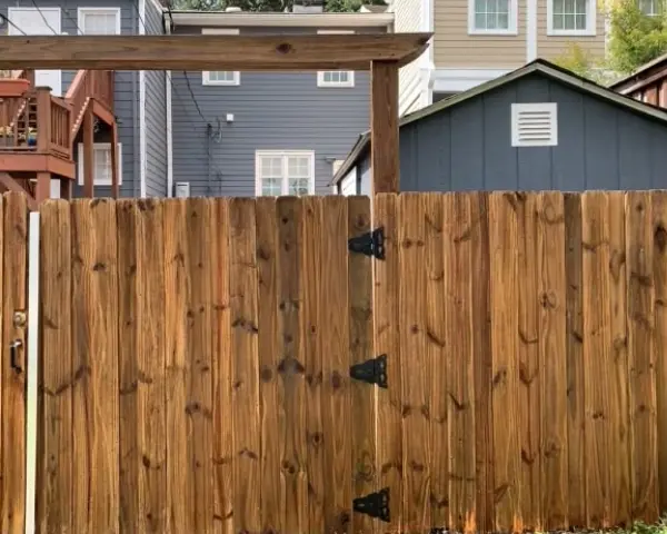 A wooden fence with two open doors and a roof.