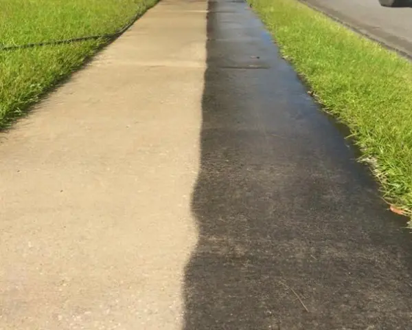 A sidewalk with grass and asphalt on it.